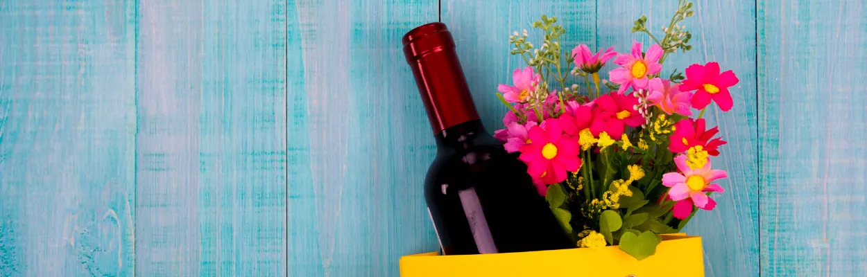 Butelka wina i bukiet kwiatów w torebce prezentowej
